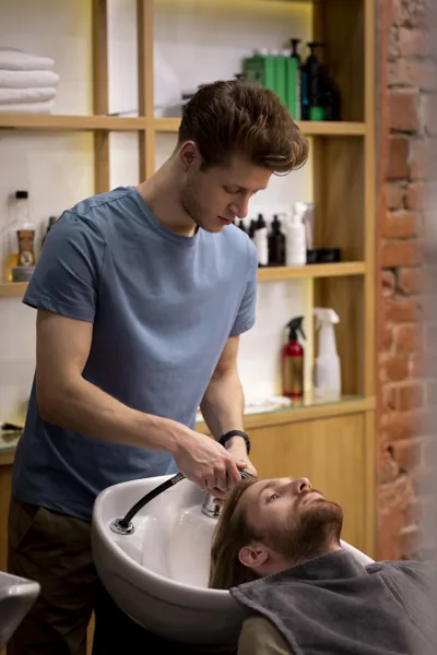 Gents salon professional providing hair and scalp treatment to a male client in a clean and relaxing salon setting.
